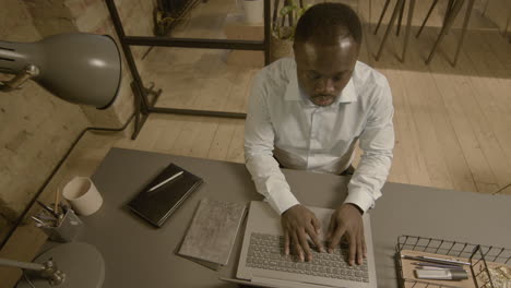 Top-View-Of-A-Serious-American-Employee-Working-On-Laptop-Computer-In-The-Office