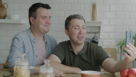 happy gay couple taking a selfie in the kitchen
