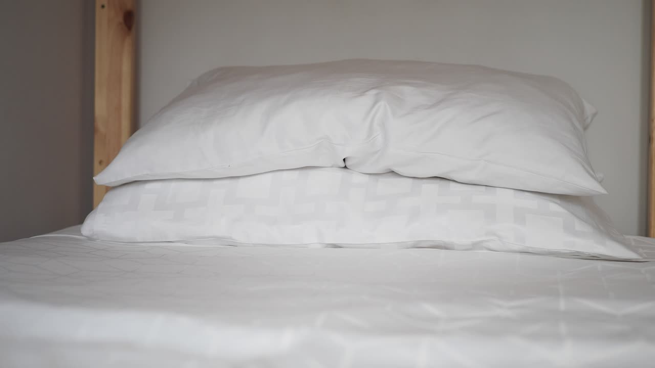 dos almohadas blancas en una cama con sábanas blancas