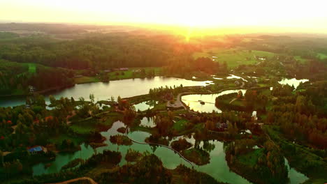 wide slow forward aerial of lakes and green forest landscape by sunset