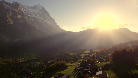 aerial drone footage dolly left to right over grindelwald village with stunning view of eiger north face at sunset