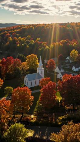 aerial view of a white church surrounded by vibrant autumn foliage at sunset