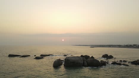 aerial drone shot capturing the stunning view of kanyakumari's cityscape and ocean during a vibrant sunset.