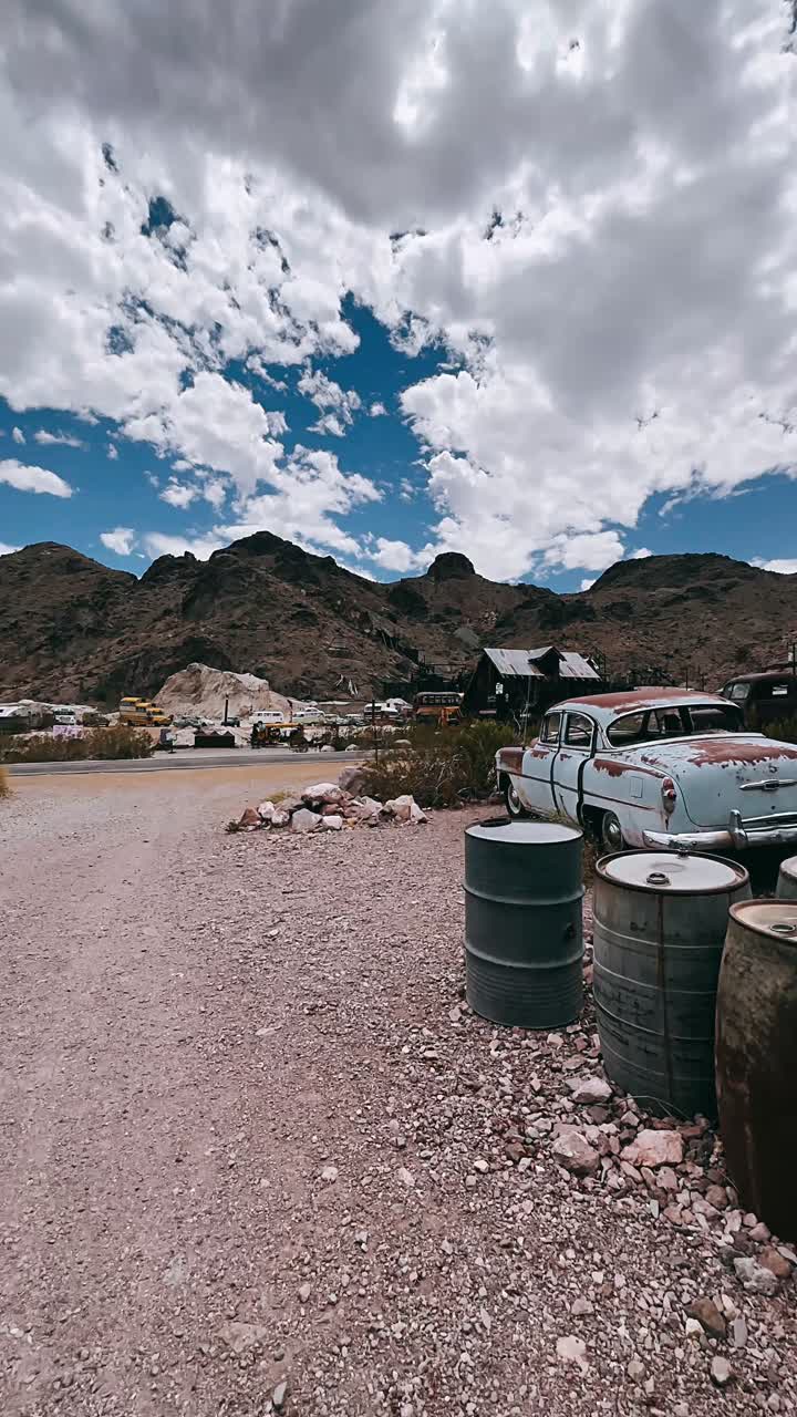 coches abandonados y barriles oxidados en un paisaje desértico
