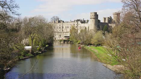 the imposing facade of warwick castle overlooking the river avon on a sunny spring day