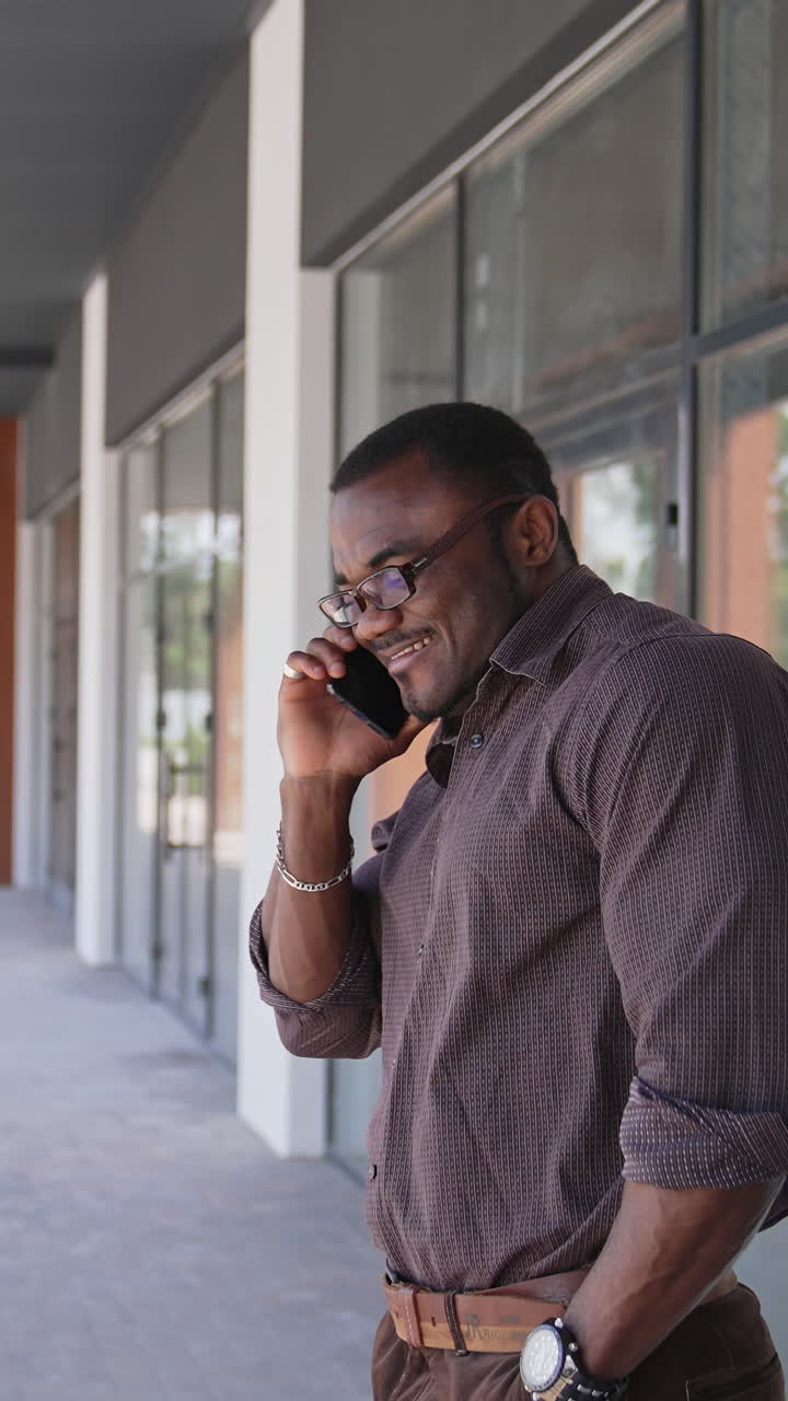 At the street. Portrait of emotionally busy businessman is talking on his phone while walking outside near glassy office centre. Successful male boss leader working outdoor and having a Busy Lifestyle Vertical video