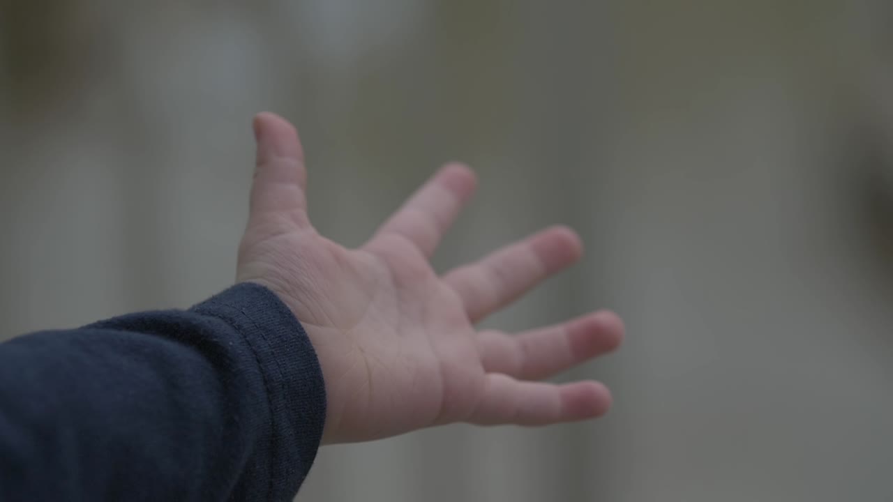 어린 소년, 어린이, 유아의 손은 비가 내리고 있는 가운데 놀고 있으며, 그의 손에는 영화 속도 느린 동작으로 비방울을 잡고 있다.