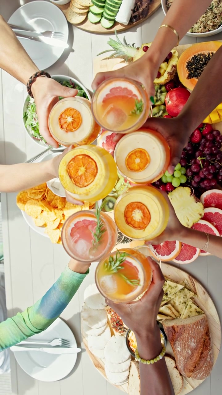 Friends Toasting with Citrus Cocktails Over a Fruit Platter