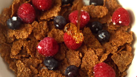 la miel se vierte en el tazón de cereales con bayas