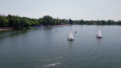 sailboats race on a lake, boat turning, parallax drone shot