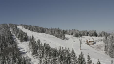 skiers going downhill on kope ski resort in pohorje mountains slovenia, aerial hovering shot