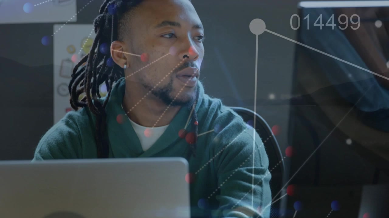 Young Man Working on Computer with Digital Data Overlay