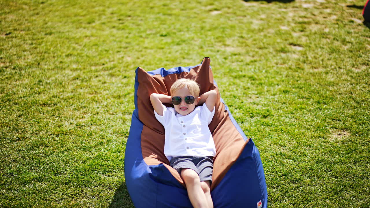 Happy Boy Relaxing in a Bean Bag Chair Outdoors