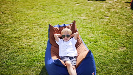 happy boy relaxing in a bean bag chair outdoors