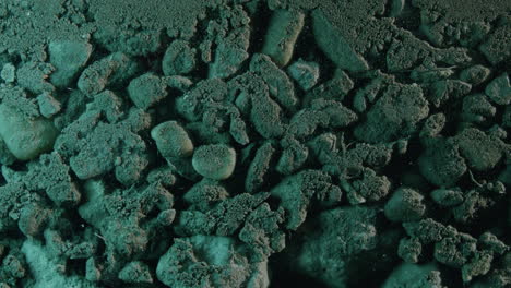 Moving-dolly-Close-up-shot-of-layered-green-lit-rocks-and-sand-underground