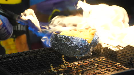 persona flameando una patata al horno rellena