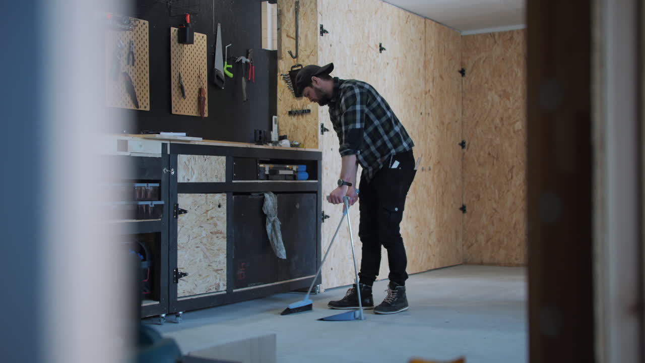 젊은 남자가 브러시로 차고를 청소하고,  ⁇ 으로 돌리