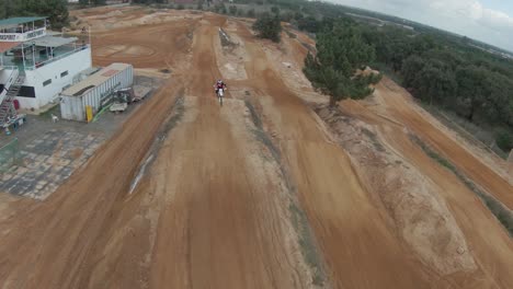 person motocross rider riding down a ramp on a dirt track on a cloudy day