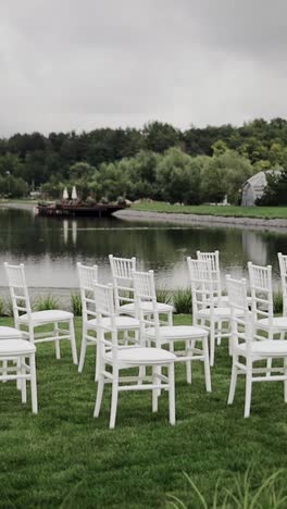 white wooden empty chairs standing on green lawn near lake