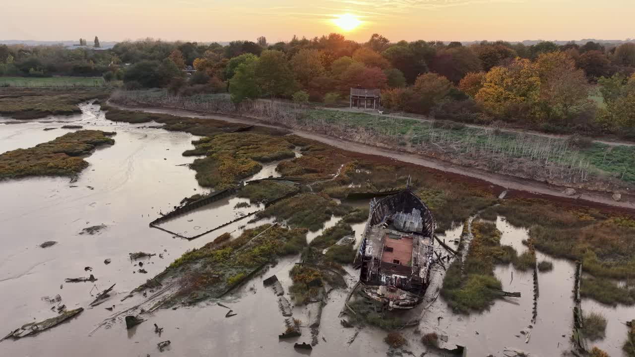 Essex saltmarsh aerial view circling Blackwater river mudflat shipwreck under glowing sunrise