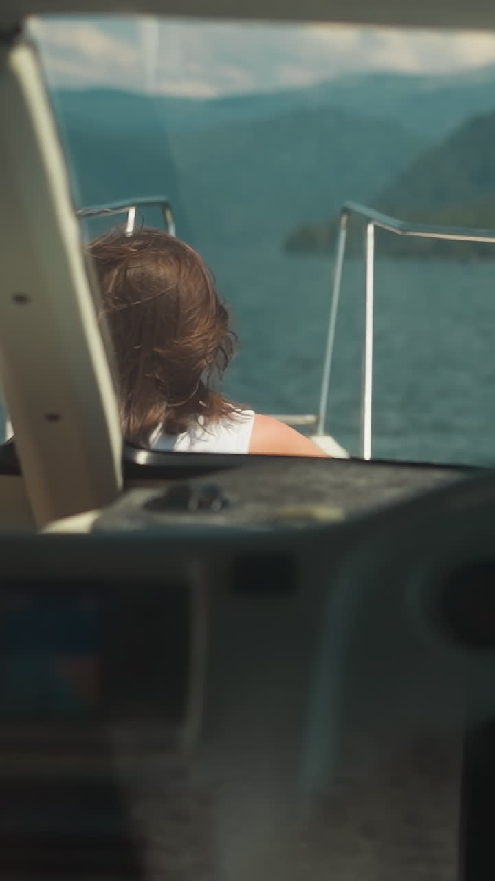 mujer turista navega en un yate contemporáneo con silueta de capitán en una laguna exótica. el pasajero descansa en la cubierta mientras el navegante profesional conduce la lancha a motor