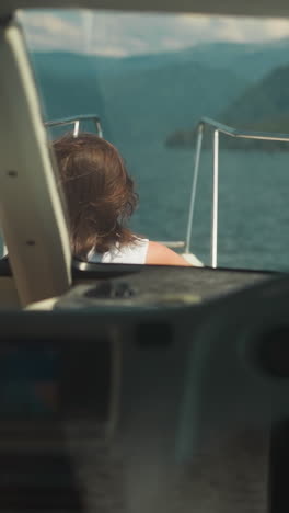 woman tourist sails contemporary yacht with skipper silhouette in exotic lagoon. passenger rests on deck while professional yachtsman drives motorboat