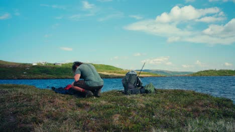 a man is gathering his camping gear on the shore of imefjelsvatnet lake in indre fosen, trøndelag, norway - static shot