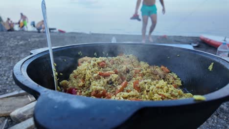 delicious pilaf cooking outdoors in a kazan on a beach campsite