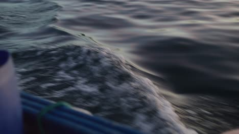 close up shot of waves in the ocean as boat sails across