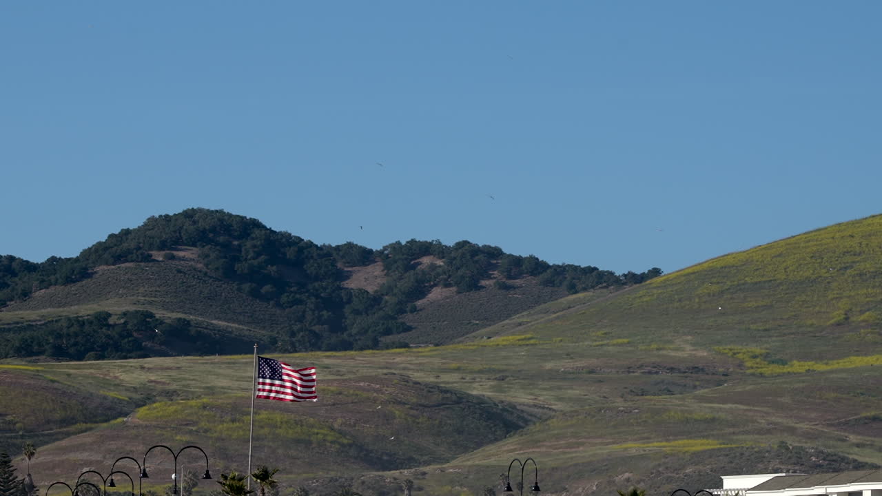 la bandera estadounidense, estrellas y rayas, vieja gloria ondeando frente a colinas y un cielo azul