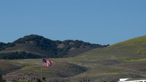 La-Bandera-Estadounidense,-Estrellas-Y-Rayas,-Vieja-Gloria-Ondeando-Frente-A-Colinas-Y-Un-Cielo-Azul