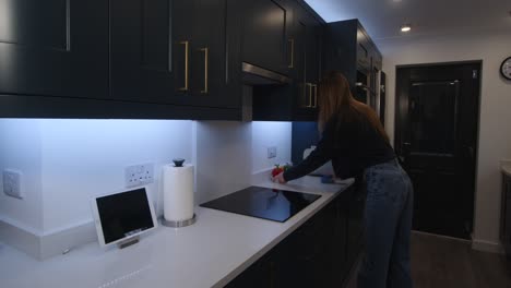 female model wiping down a white quartz worktop by a induction cooker top in a kitchen