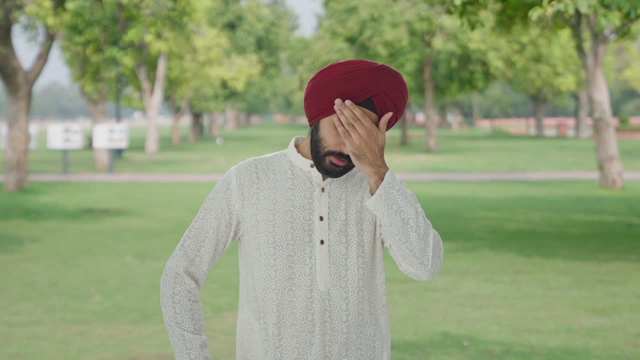 Sick Sikh Indian man suffering from headache in park