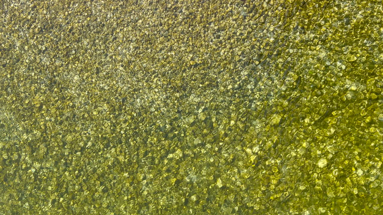 vista superior del arroyo del río de la montaña con guijarros en el fondo