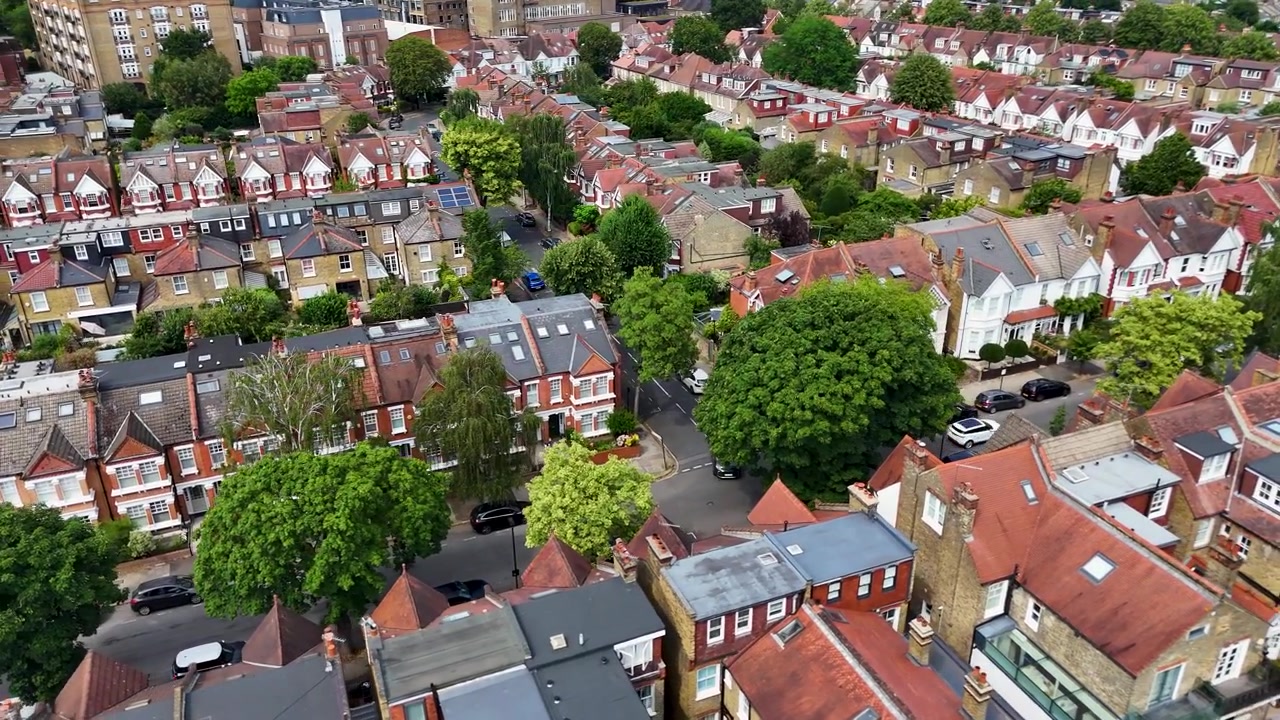 Case a schiera con tetti in ardesia e piccoli giardini posteriori circondano un albero maturo sulla strada in un tranquillo isolato residenziale di Londra ovest