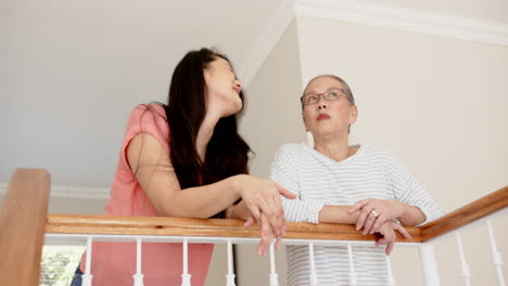talking and leaning on railing, asian grandmother and granddaughter enjoying conversation at home