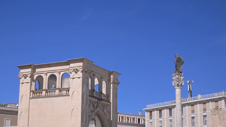 Gli archi del Sedile e la Colonna di Sant'Oronzo si stagliano contro un cielo azzurro limpido in Piazza Sant'Oronzo, a Lecce