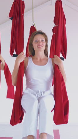 nice women have fun swinging on red hammocks prepared for modern anti-gravity yoga in white spacious room