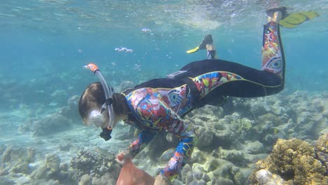 woman in diving equipment swims and collects plastic debris underwater on the bottom of coral reef. snorkeler cleaning ocean from plastic pollution. plastic pollution of the ocean (4k-60fps)