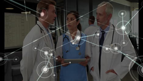 female nurse holding tablet while male doctors consulting in medical lab displaying network overlay
