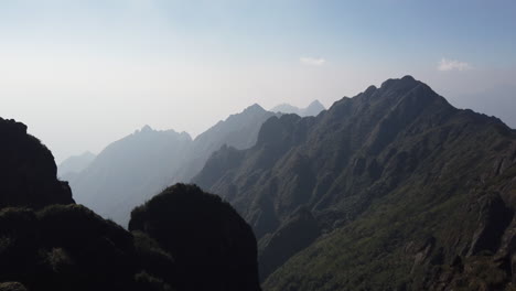 looking out along epic mountain range, jagged rocks, green on a misty blue sky day, fanispan, sapa, vietnam