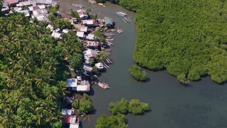 Aerial-drone-footage-flying-over-Day-Asan-Floating-Fishing-Village-in-Surigao-Del-Norte-with-lush-trees-and-colourful-metal-roofs-in-shot