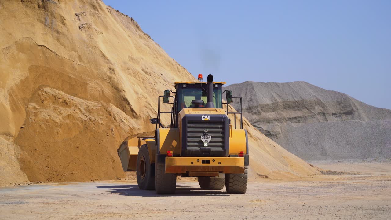 Outdoor asphalt mixes station. Industrial asphalt plant surrounded by piles of gravel