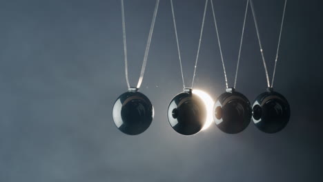 balls in newton's cradle hit each other in the light of the spotlight beam