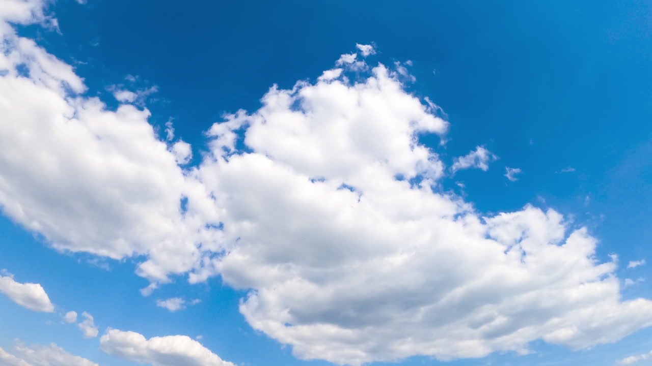 Amazing azure sky with white fluffy clouds. Sun shining brightly and lighting the clouds. Low angle view timelapse.