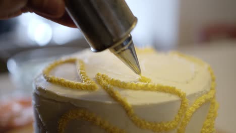 close up of cake being decorated with yellow frosting