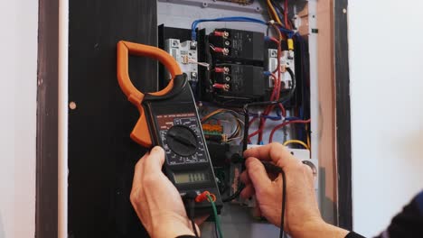 los electricistas ponen las manos a probar la corriente eléctrica en el panel de control. el ingeniero electricista trabaja midiendo el voltaje y la corriente de la línea eléctrica en el control del gabinete eléctrico.