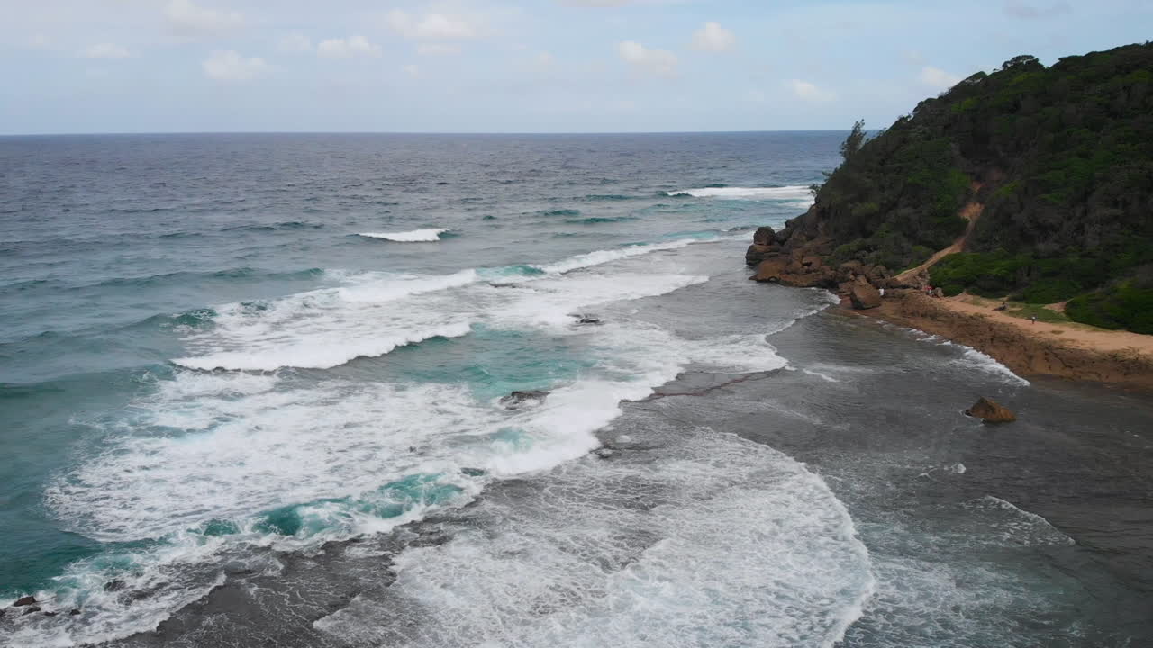 barrido rápido hacia abajo vista aérea del océano con el agua golpeando la pared de la roca a medida que sube la marea