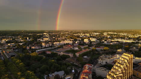 the sunlit city of montpellier lies beneath a picturesque rainbow.