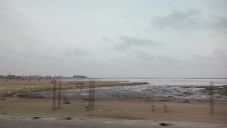 a shot from a car of the dakar coast, that shows the beach, with people walking, and outdoor fitness equipment